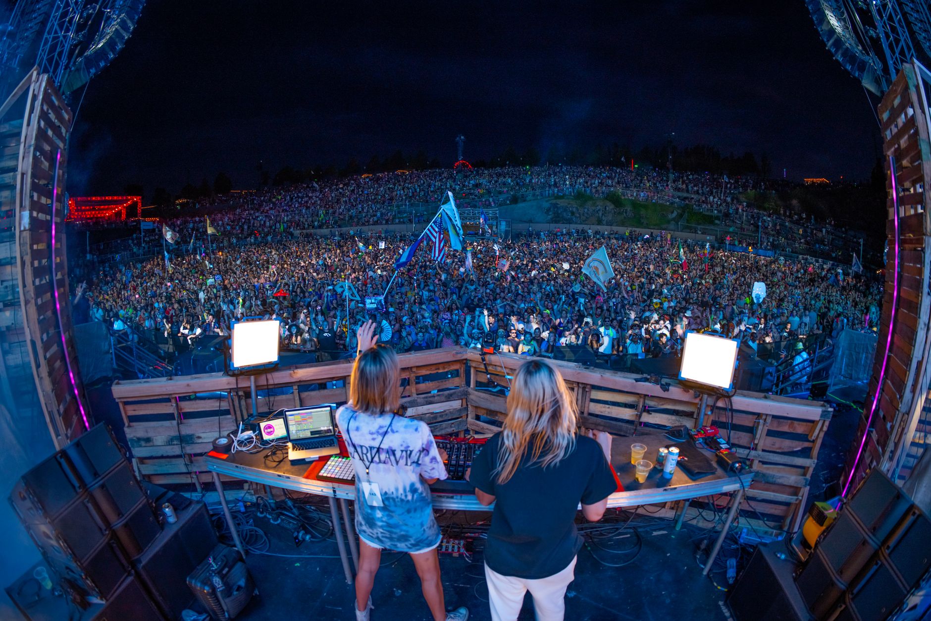 View from behind the decks of a hillside amphitheatre packed to the back fence at dusk